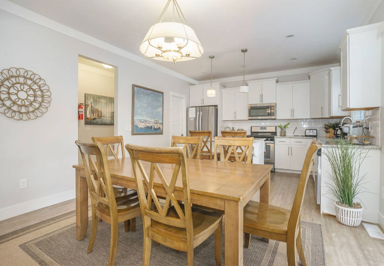 Dining room with wooden table and chairs, open to bright modern kitchen with white cabinets at Bridgewater Cottage