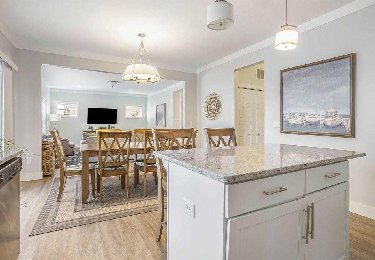 Kitchen and dining area with large island, wooden dining table, and open view into living room at Bridgewater Cottage