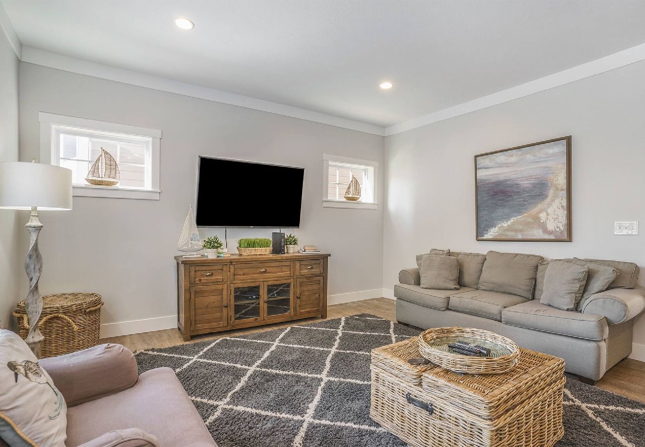 Living room with sofa, accent chair, large TV, and wicker coffee table at Bridgewater Cottage