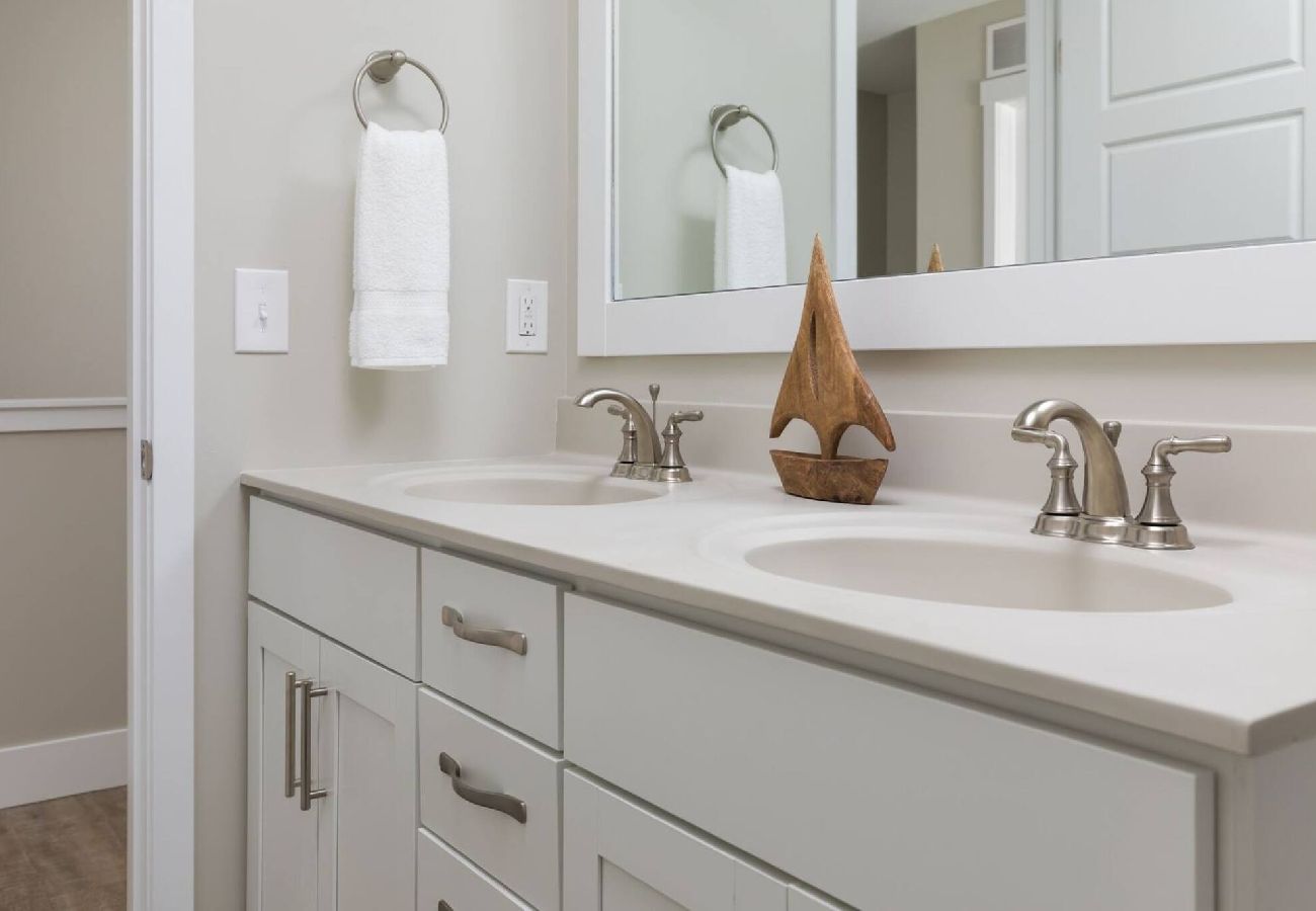 Main level bathroom with double-sink vanity and coastal decor at Bridgewater Cottage