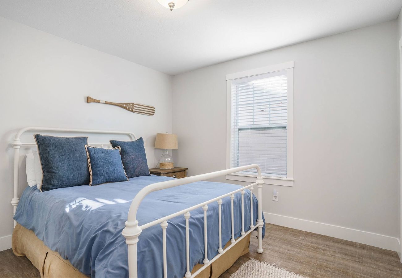 Bedroom with metal-frame and blue bedding at Bridgewater Cottage