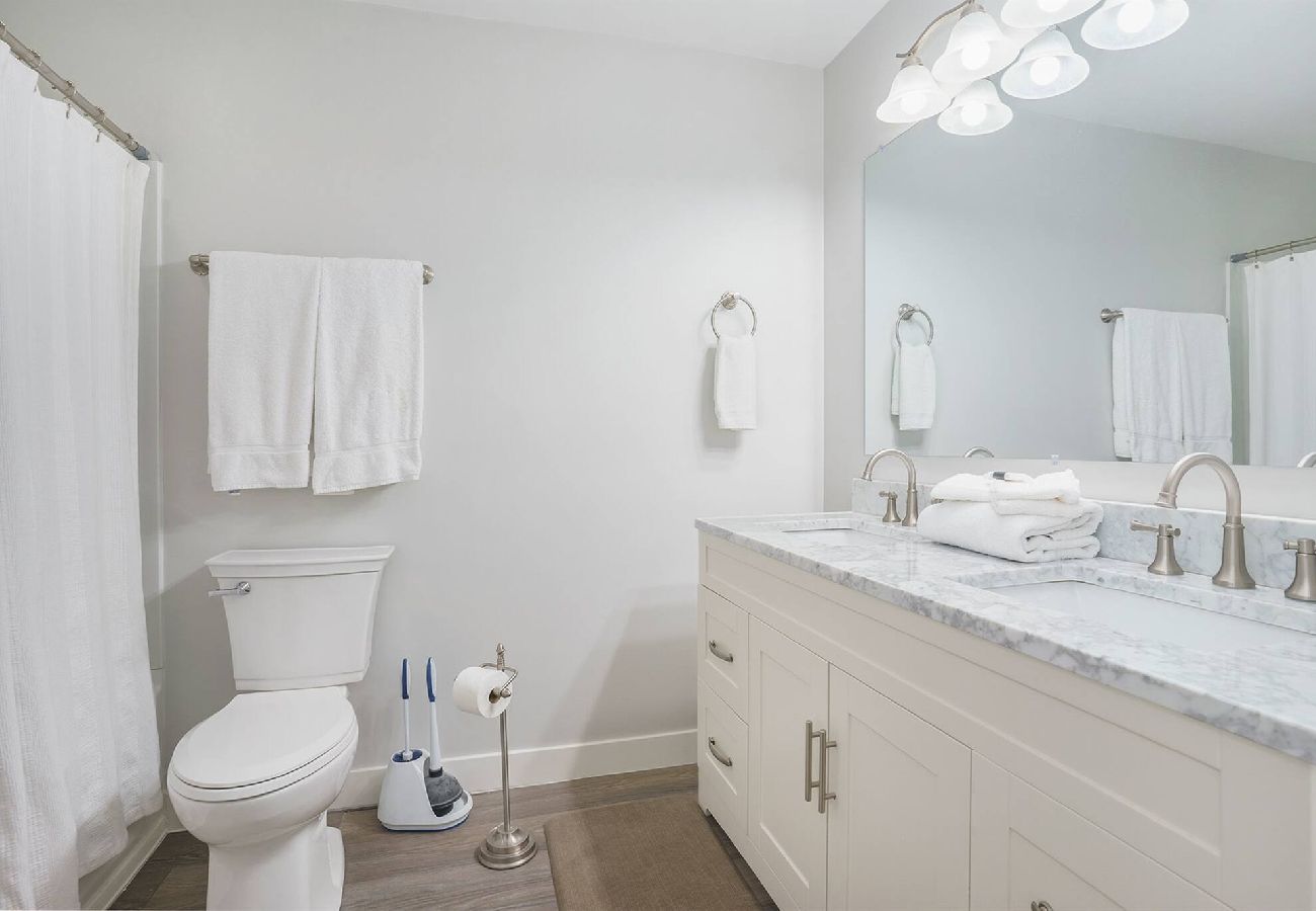 Bathroom with double-sink vanity, marble countertops, and shower/tub at Bridgewater Cottage