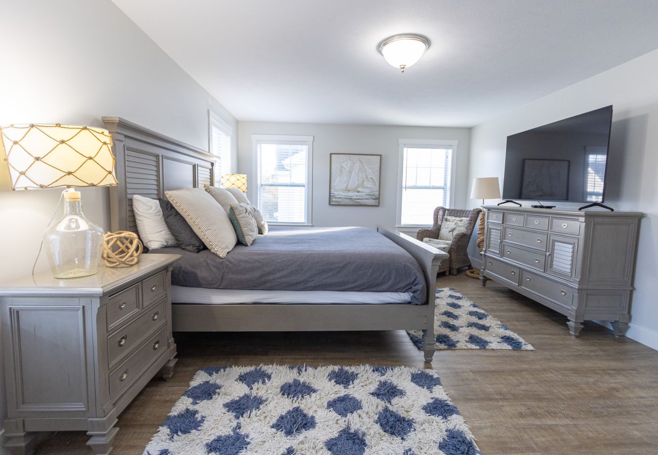  Primary bedroom with king bed, coastal decor, and en-suite bathroom at Bridgwater Cottage 
