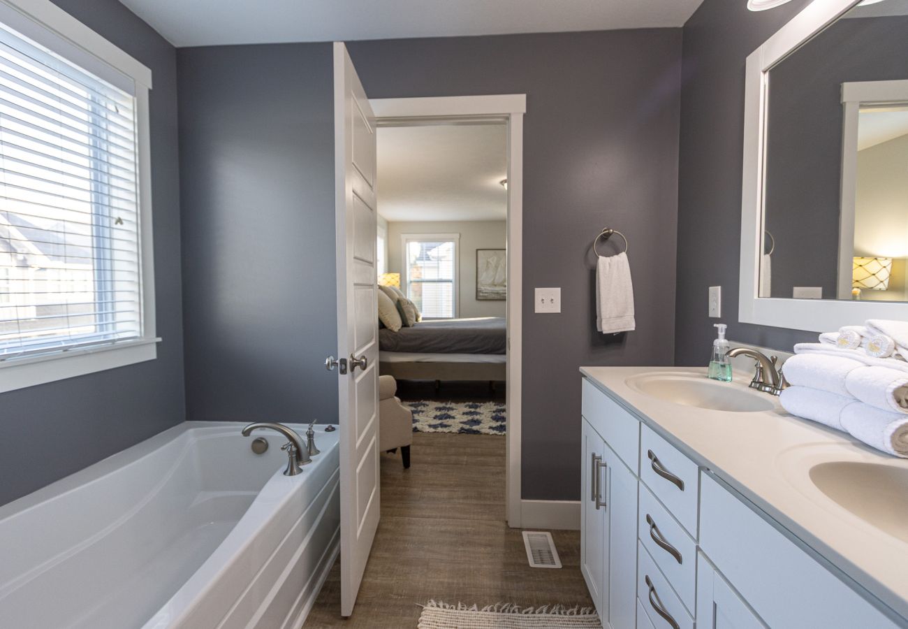 En-suite bathroom featuring a double vanity,soaking tub, and gray walls connected to the primary bedroom in Bridgewater 