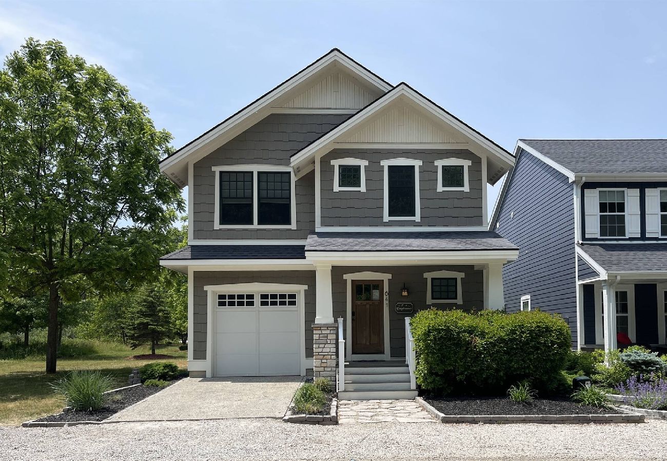 Front exterior of Daydreamer Cottage, a two-story home with covered porch and garage