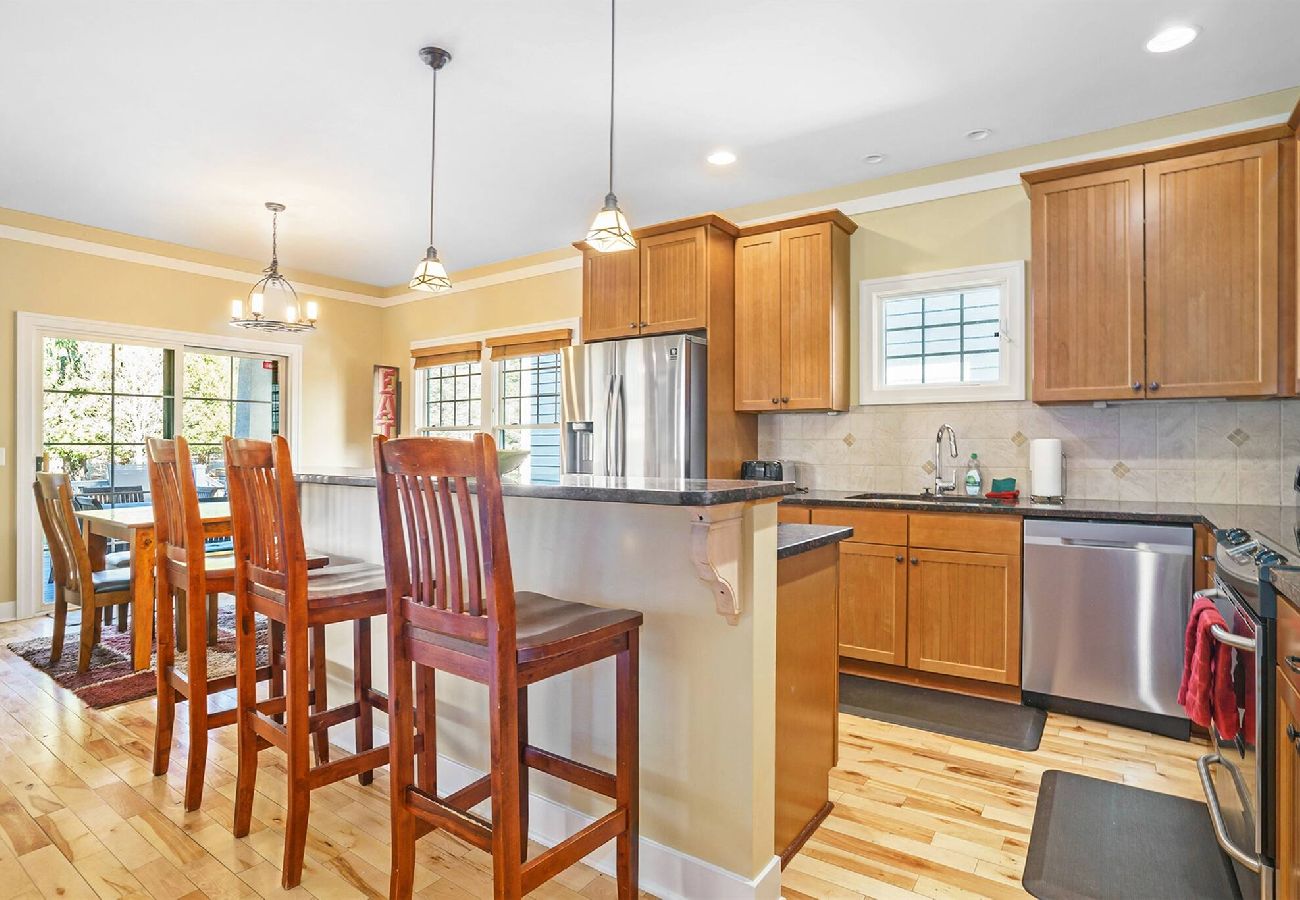 Open kitchen with wood cabinets, stainless steel appliances, island seating, and adjacent dining area at Daydreamer