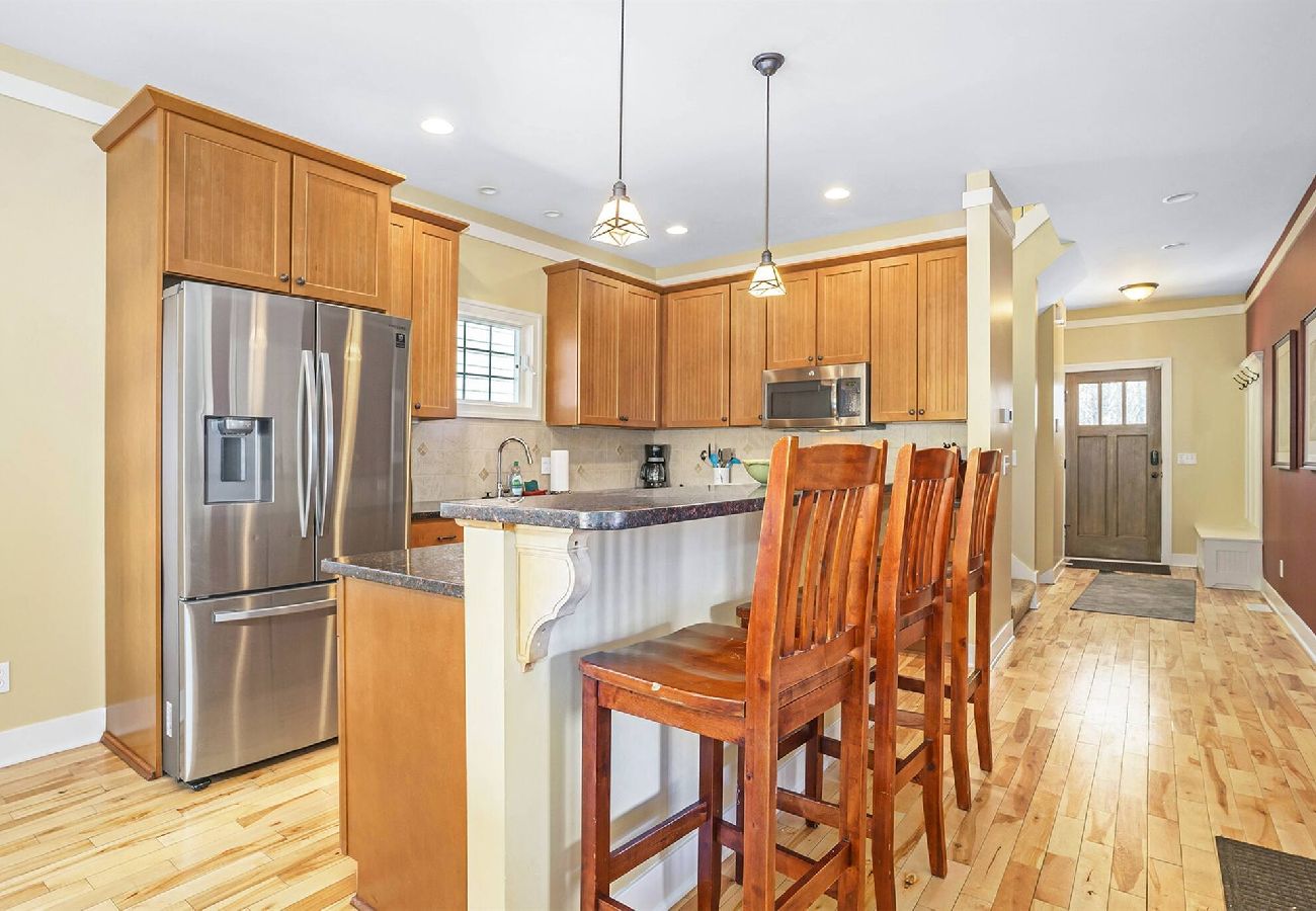KItchen with stainless appliances, wood cabinets, and island seating at Daydreamer Cottage