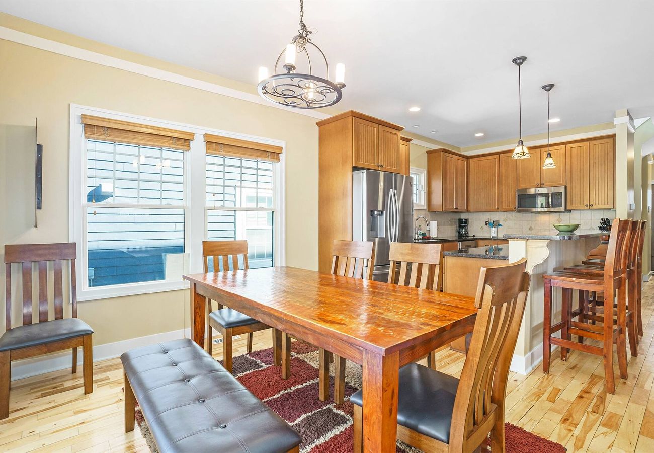 Dining area with large wooden table, bench seating, and view into the open kitchen