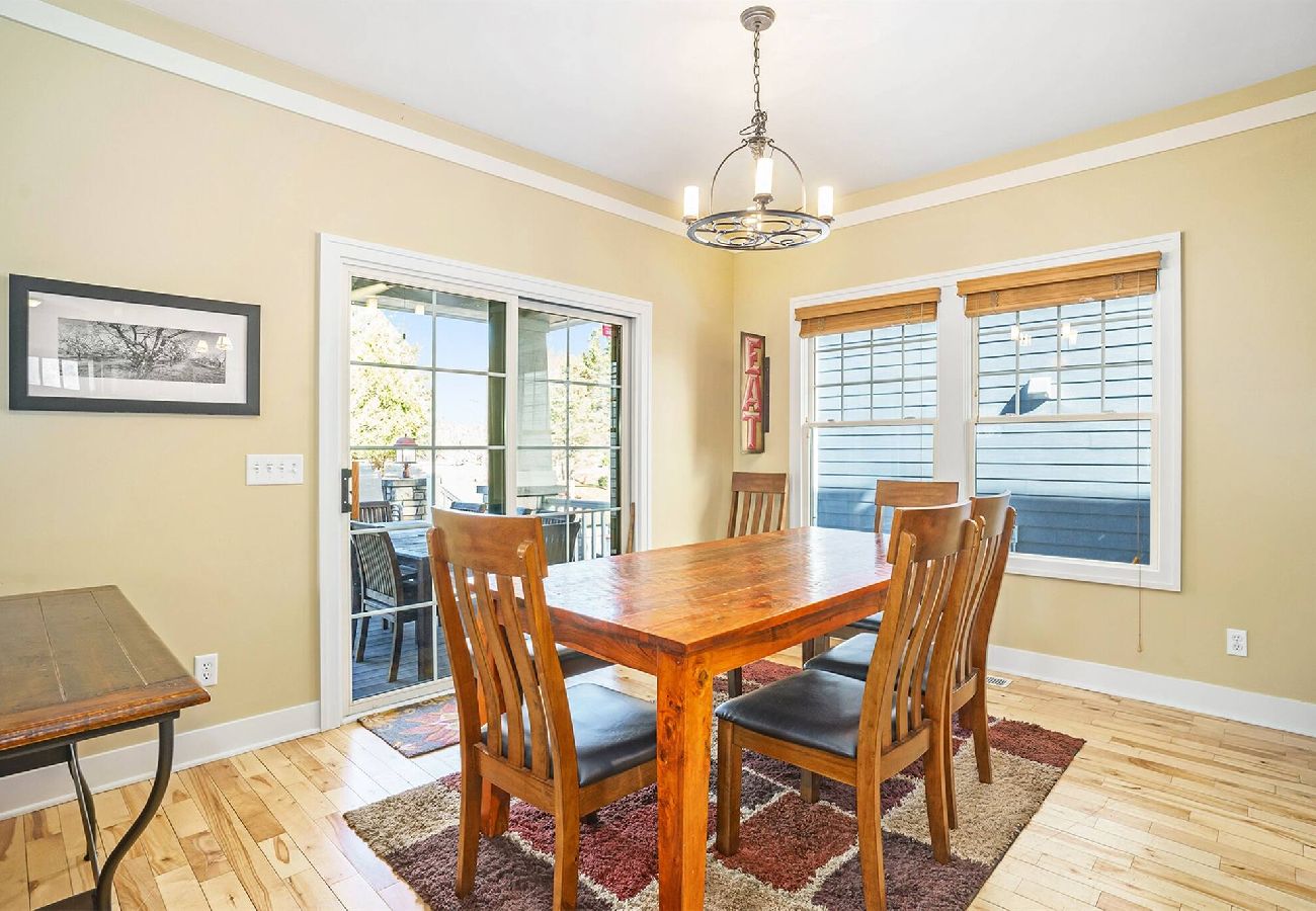 Dining room with large wooden table, chairs, and sliding doors leading to the outdoor patio at Daydreamer Cottage