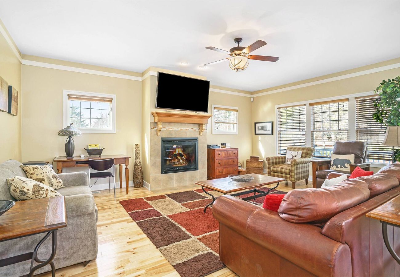 Bright living room with fireplace, leather and upholstered seating, large windows, and cozy decor at Daydreamer Cottage