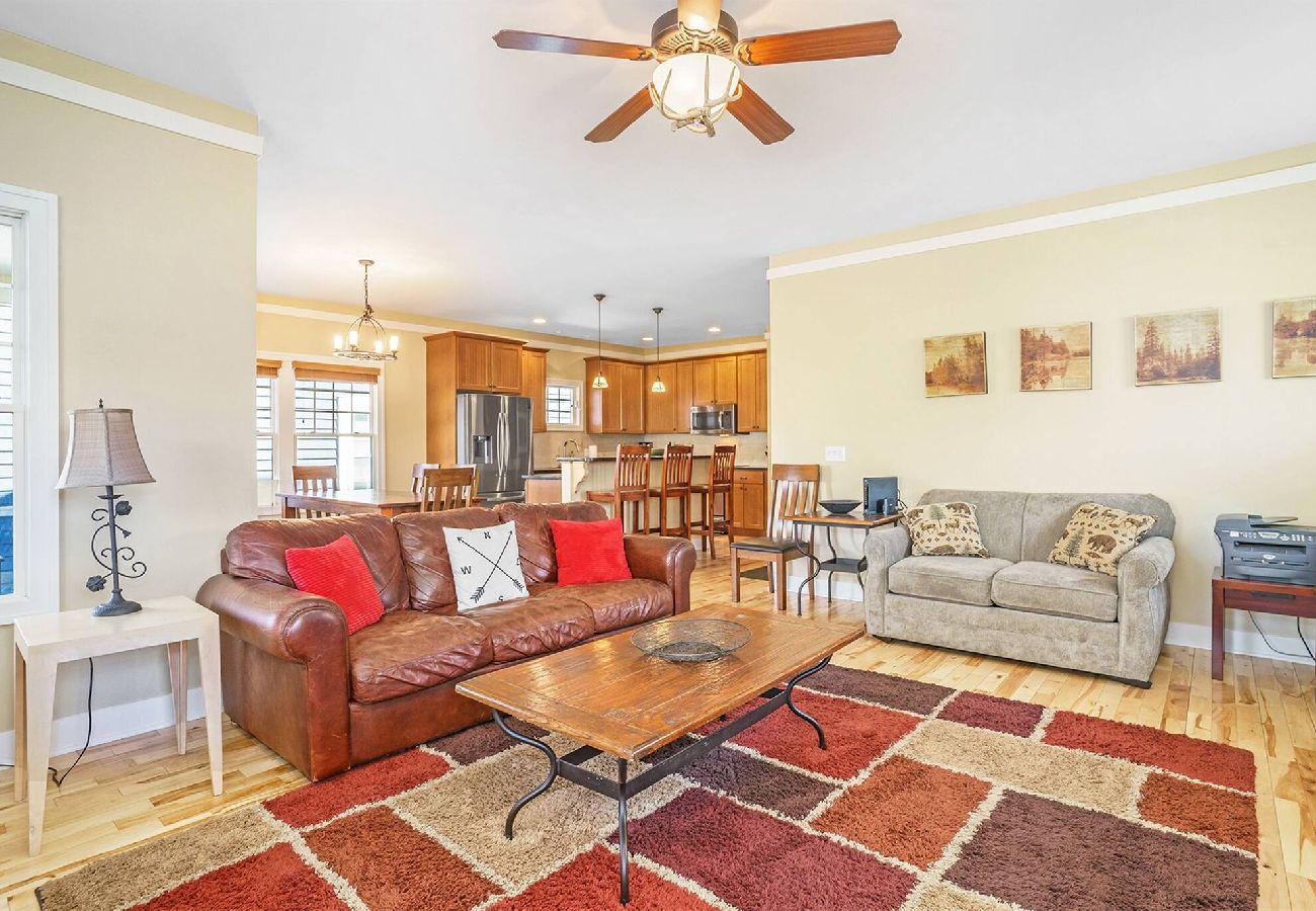 Open living space with leather sofa, loveseat, patterned rug, and view into kitchen and dining area at Daydreamer