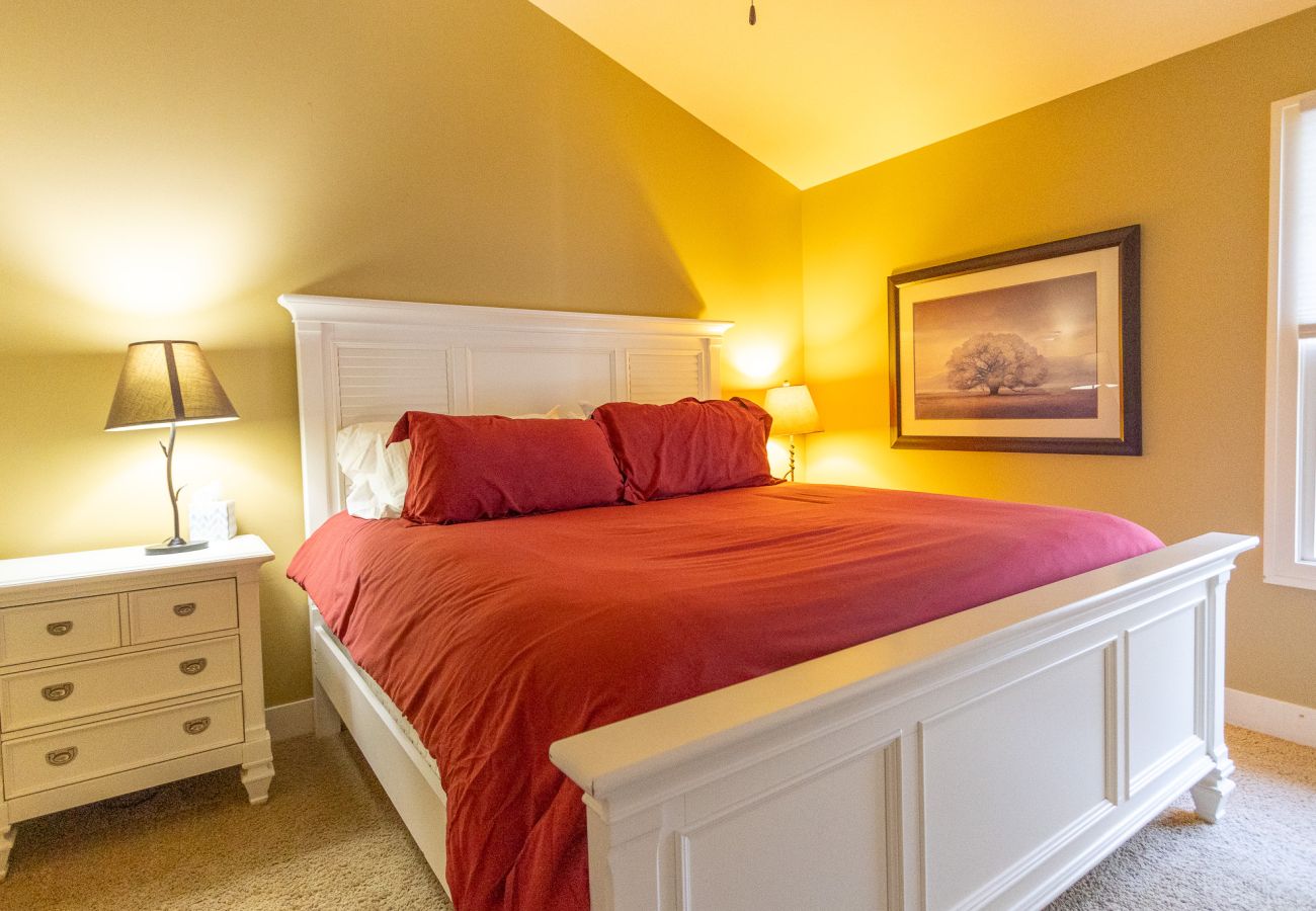 Queen bedroom with white bedframe, red bedding, and nightstands 