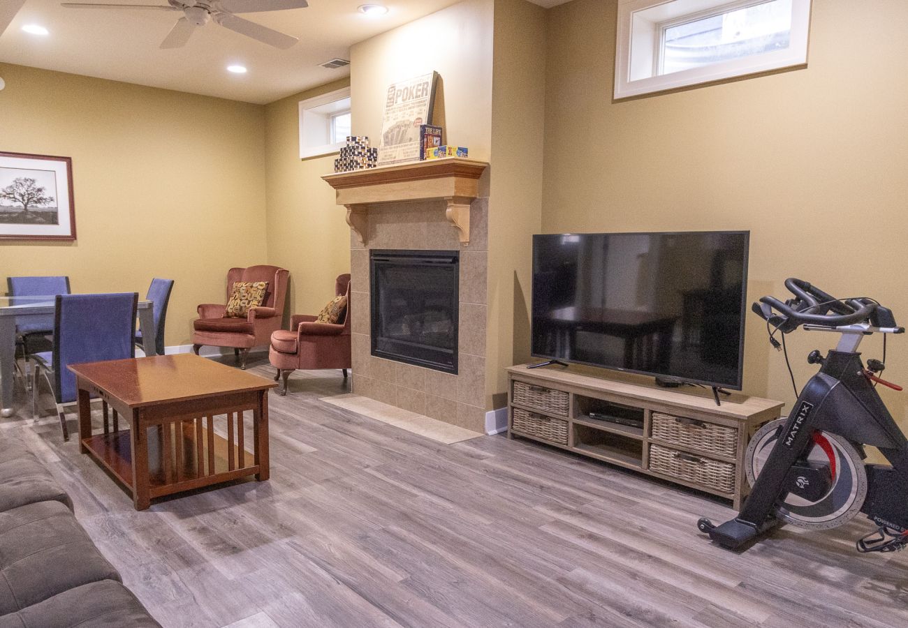 Basement living room with fireplace, smart TV, dining table and exercise bike at Daydreamer Cottage 
