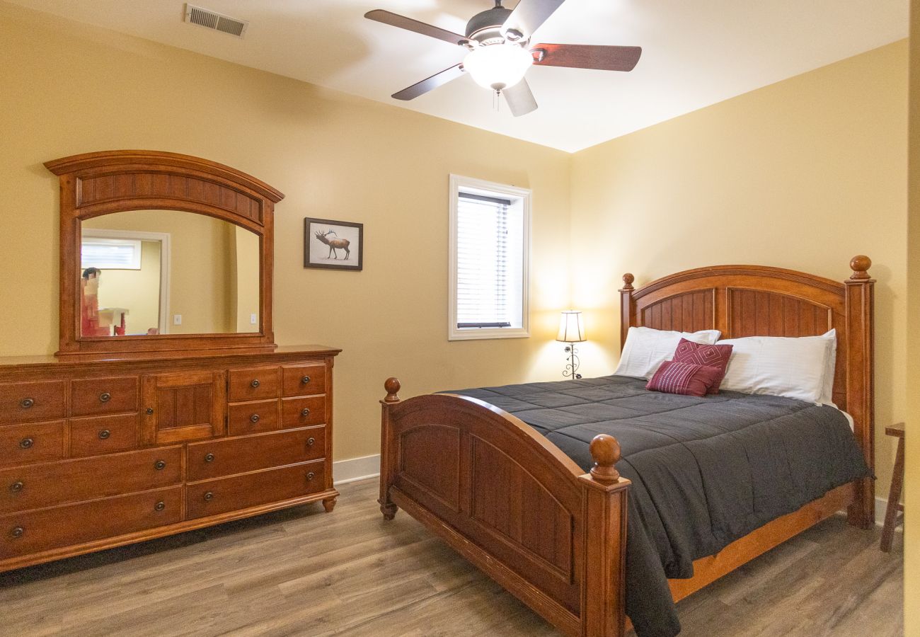 Basement bedroom with a wooden queen bed, neutral walls, and ceiling fan 