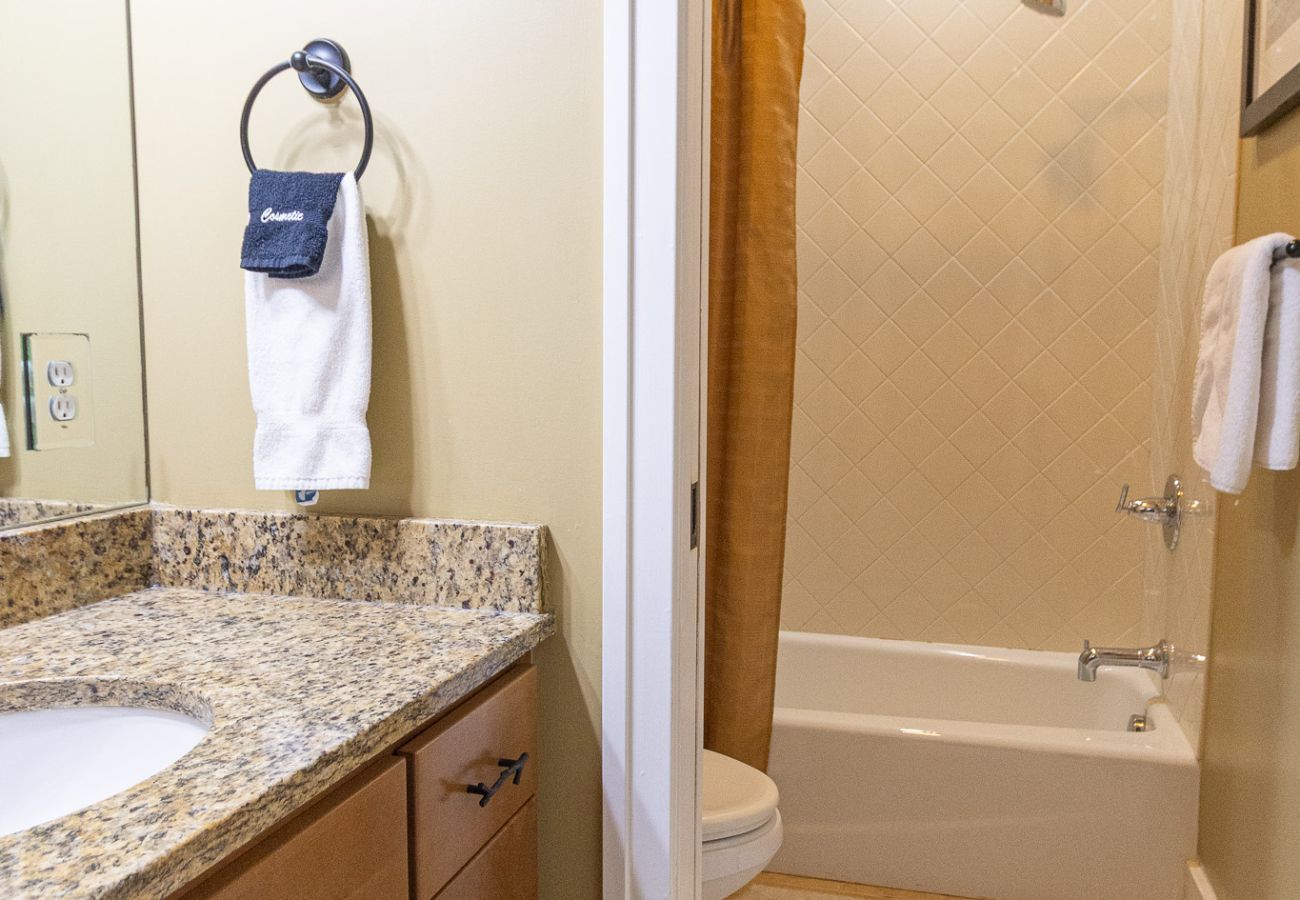 Basement bathroom featuring a granite vanity, mirror, and a tub/shower combo 