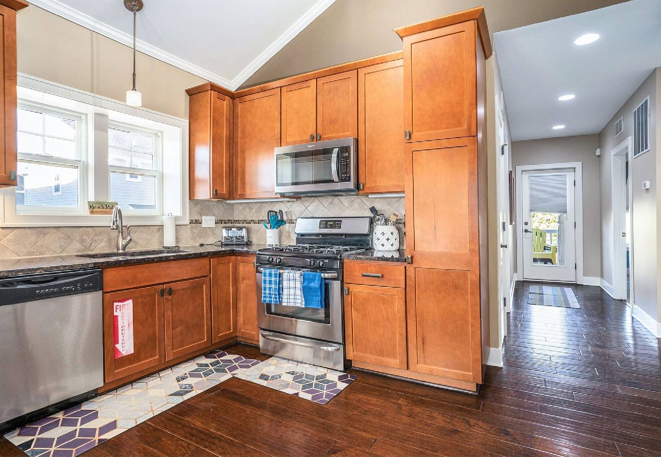 Kitchen with wooden cabinets, stainless steel appliances, and a hallway leading to back door