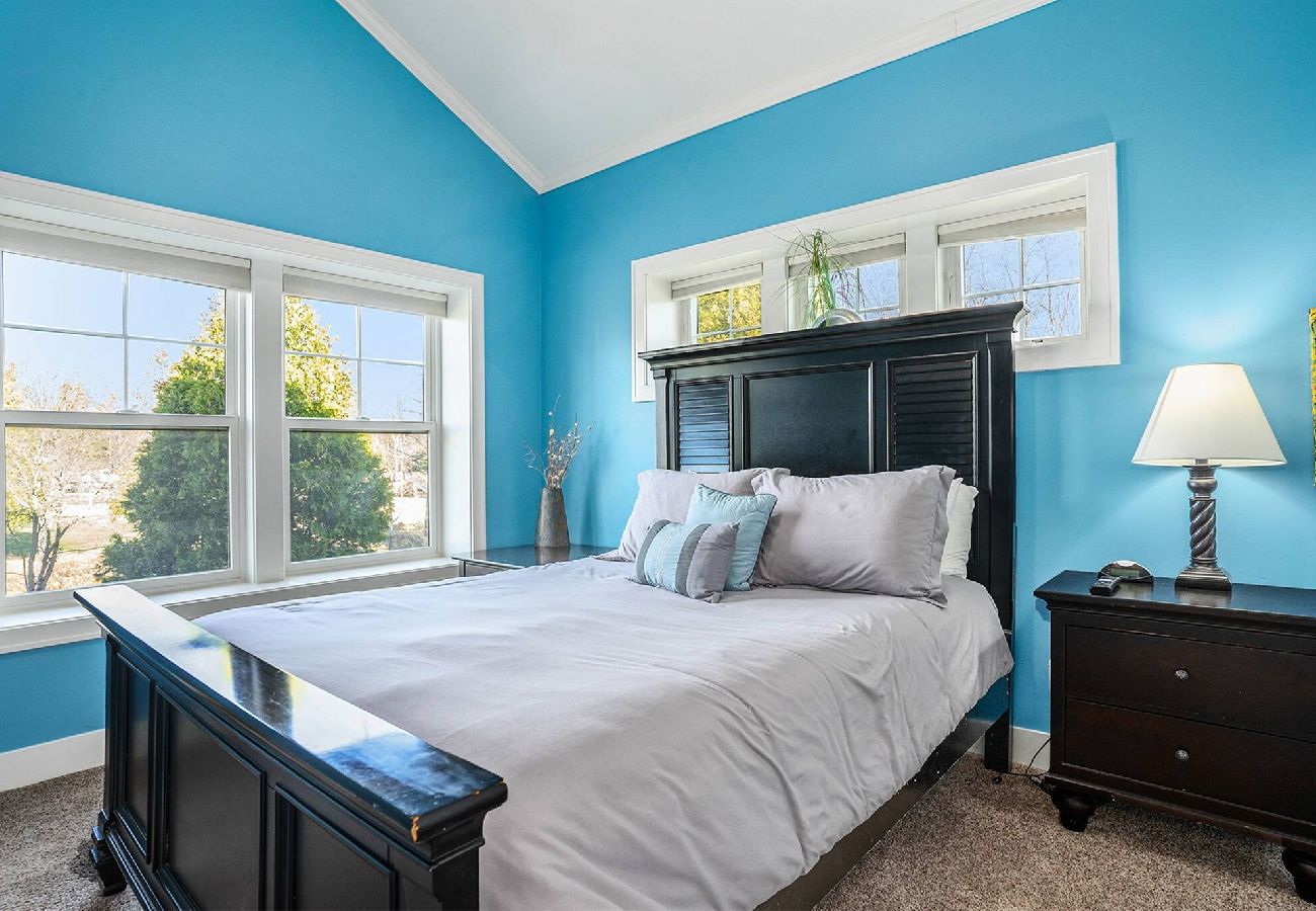 Primary bedroom with queen bed, vaulted ceiling, and en-suite bathroom access