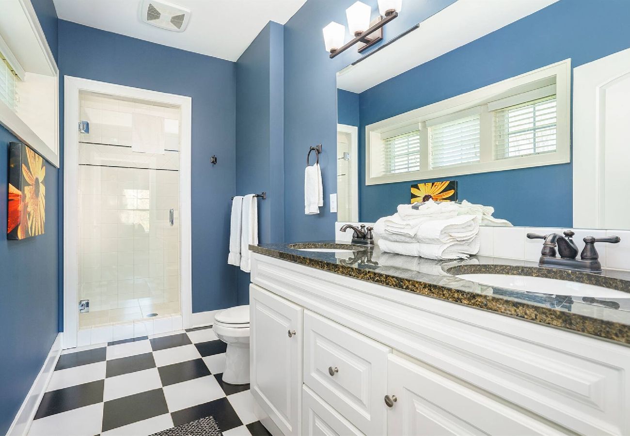 En-suite bathroom with double-sink vanity, walk in shower and checkered tile flooring at Wildflower cottage in South Haven