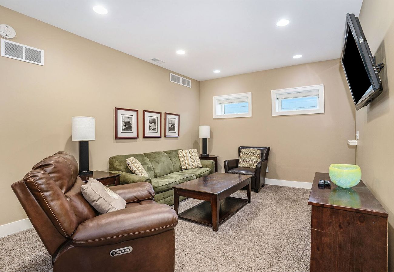 Basement living room with recliner, sofa seating, and mounted TV