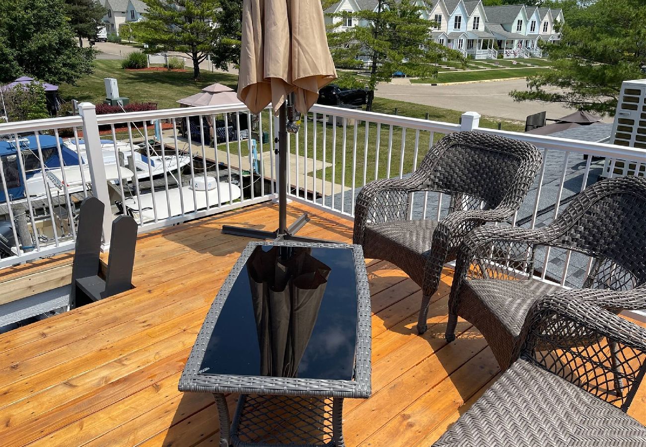 Rooftop Patio at Morning Glory tiny floating cottage with wicker seating, glass-top table and marina views