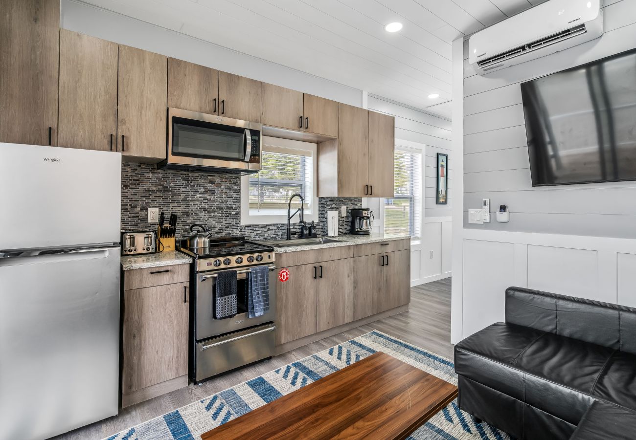 KItchen with full appliances, wood cabinets, tile backsplash, and adjacent living area at Morning Glory Floating Cottage 