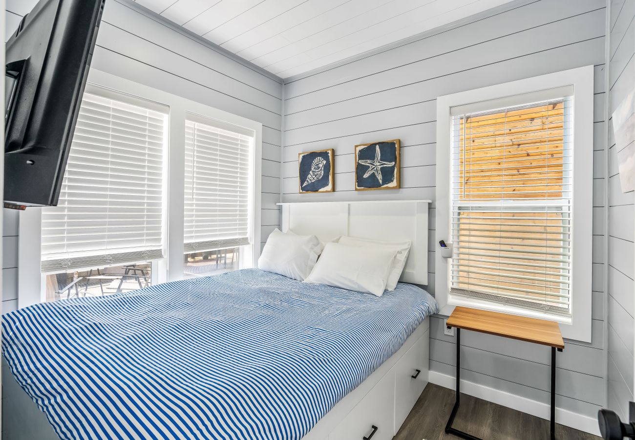 Cozy nautical-themed bedroom with striped bedding, shiplap walls, natural light at Morning Glory Floating