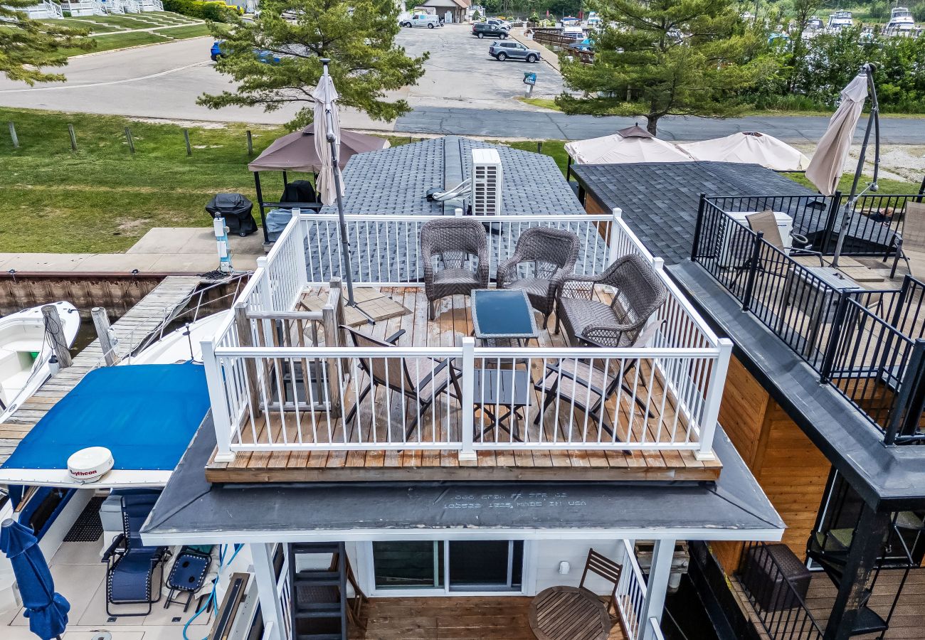 Rooftop deck of Morning Glory Floating Cottage with wicker seating and marina views in South Haven, Michigan