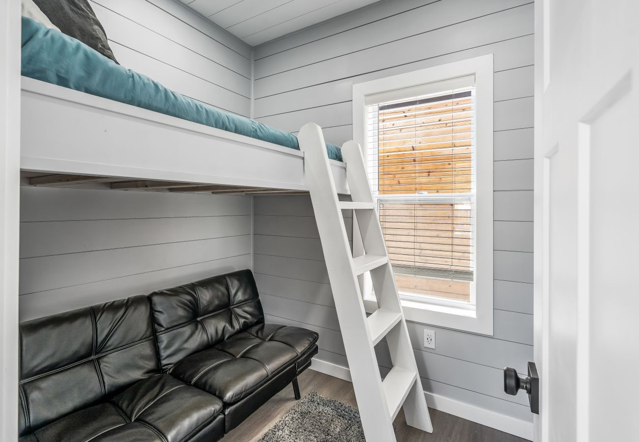 Lofted bunk bed with ladder and black futon seating in the bunk room at Morning Glory