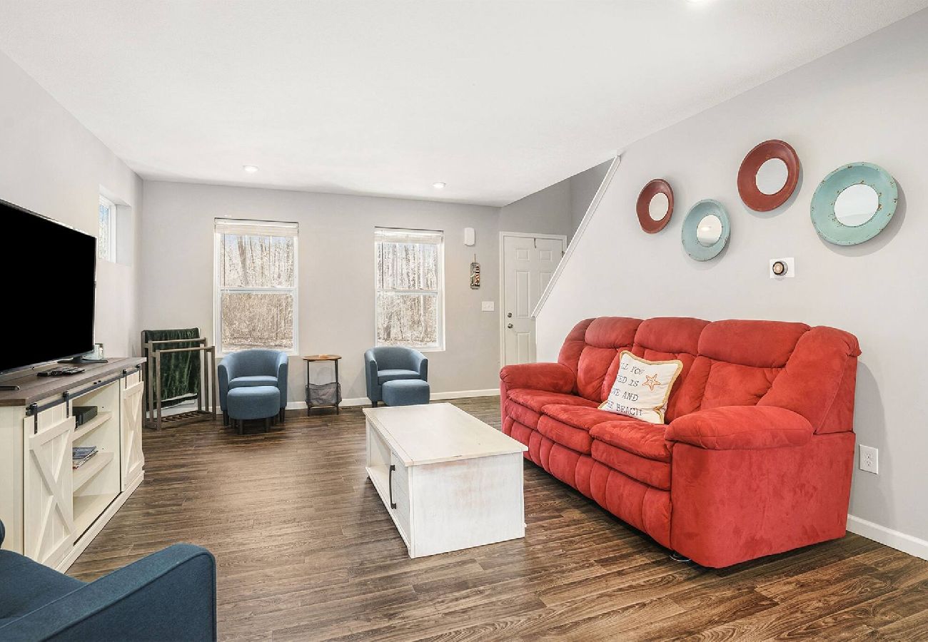 Living room with red sofa, blue accent chairs, white entertainment center, and wall decor