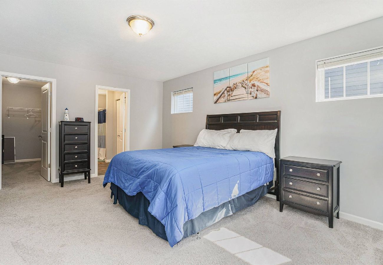 Primary bedroom with blue bedding, dark wood furniture, walk-in closet, and attached bathroom