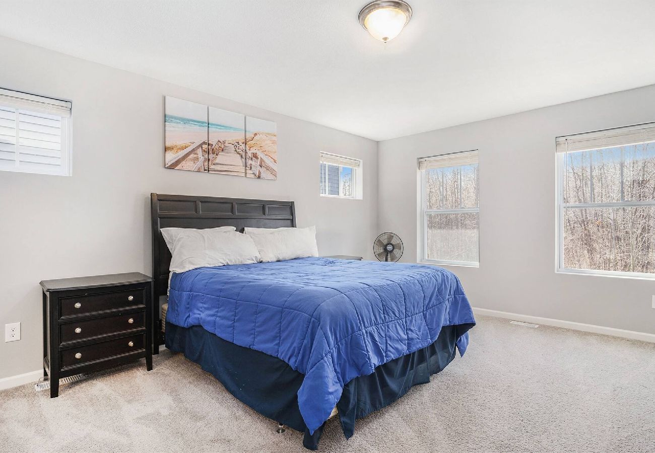 Primary bedroom with multiple bright windows overlooking wooded views