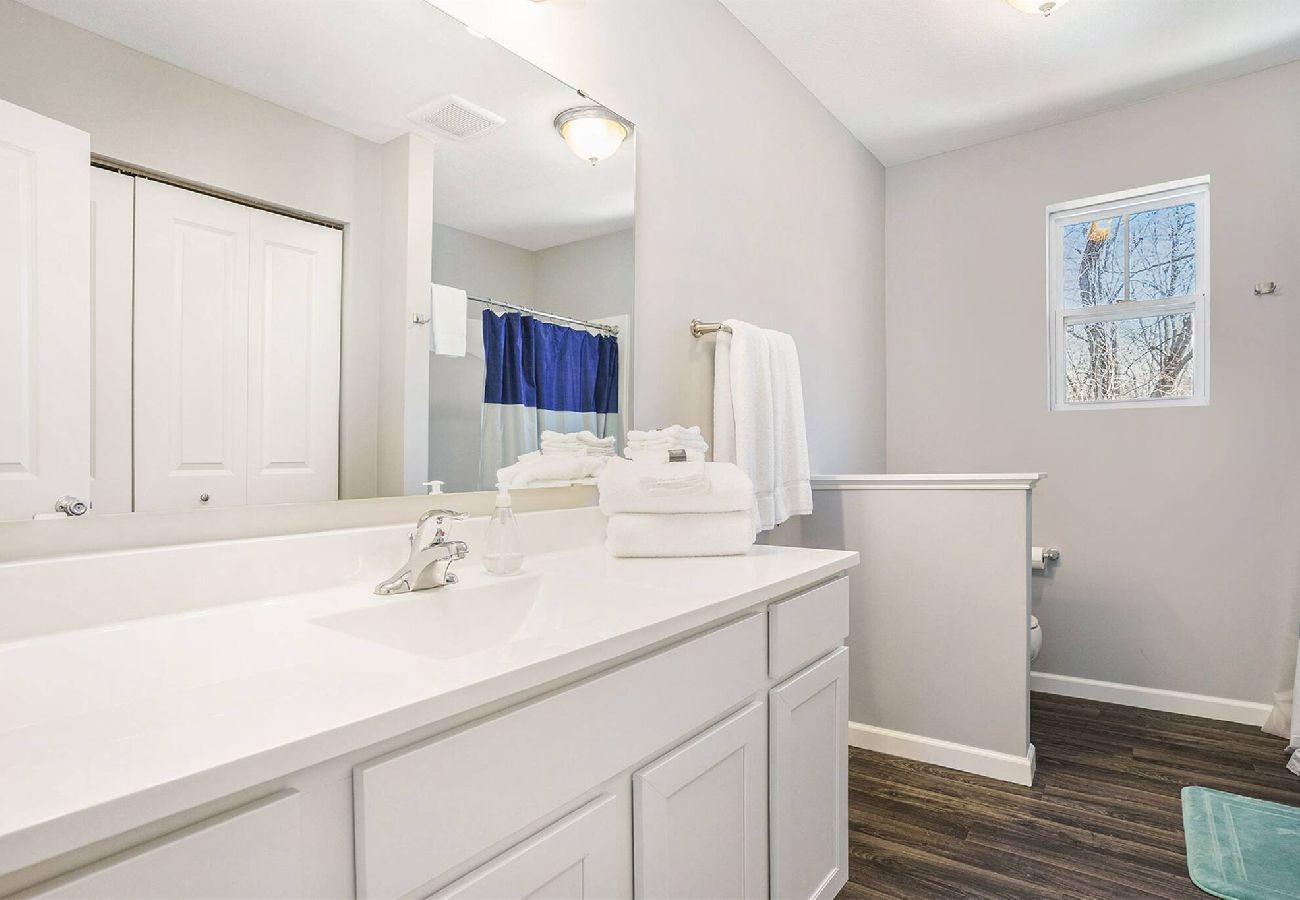 Bathroom with white double vanity, and wood-look flooring