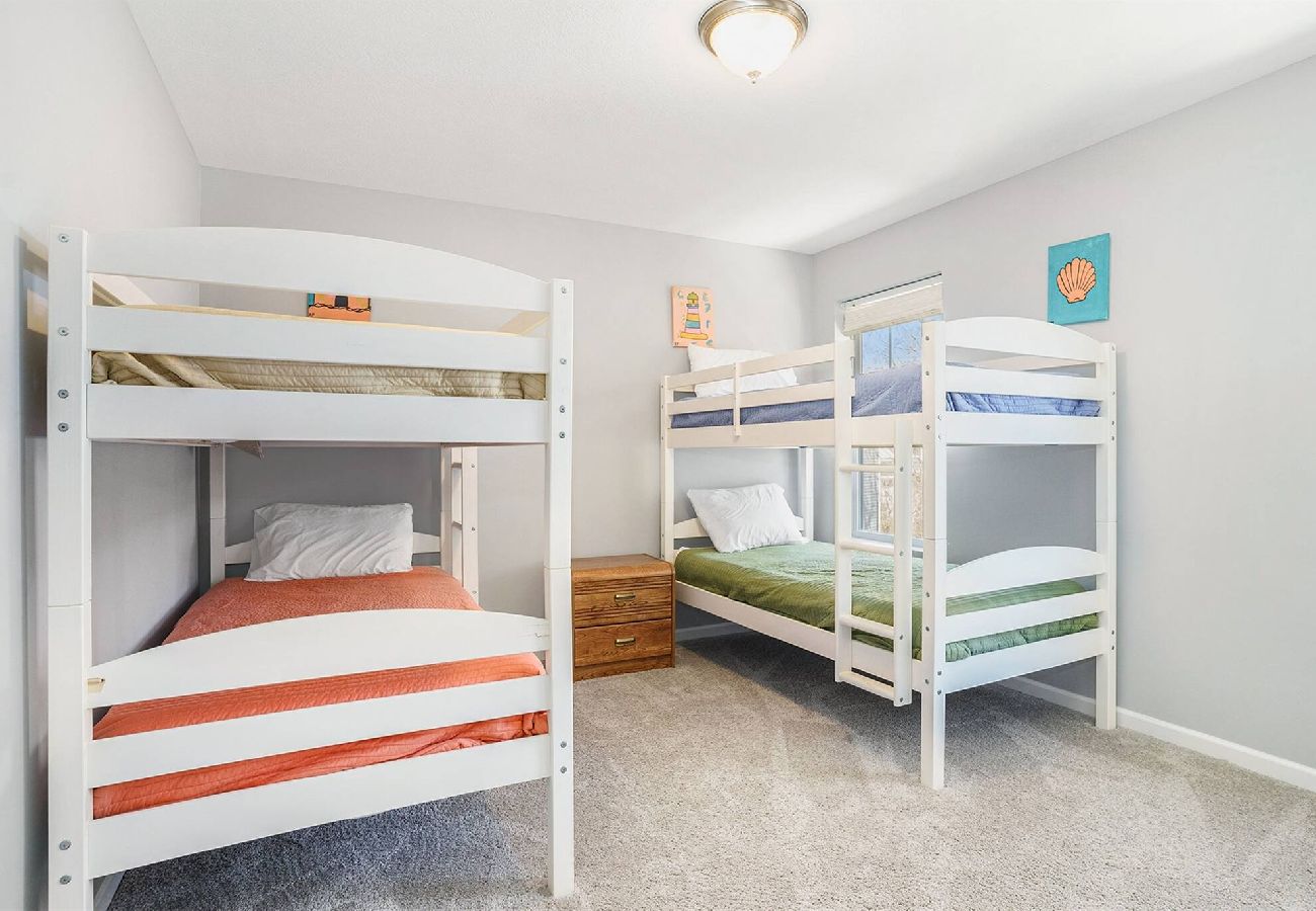 Bedroom with two white bunk beds sets, and colorful bedding