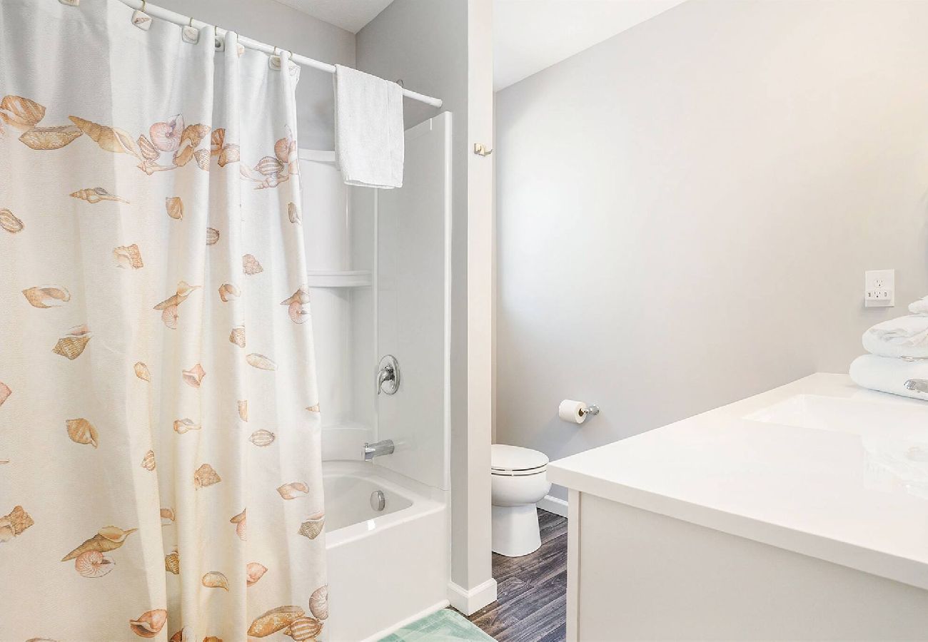 Bathroom with white vanity, tub/shower combo with seashell curtain