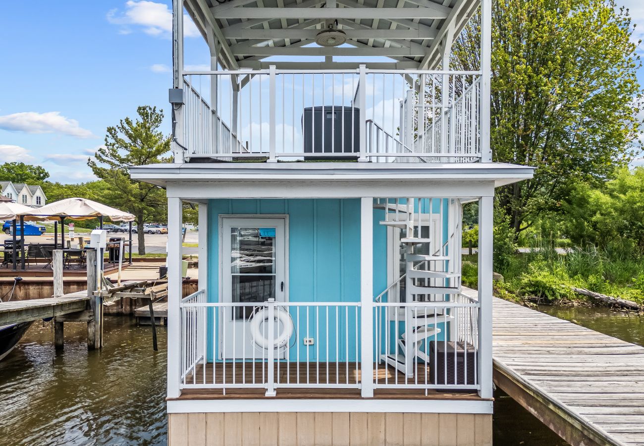 Aqua Vista floating cottage exterior with spiral staircase, lower patio. and covered upper deck in South Haven, Michigan