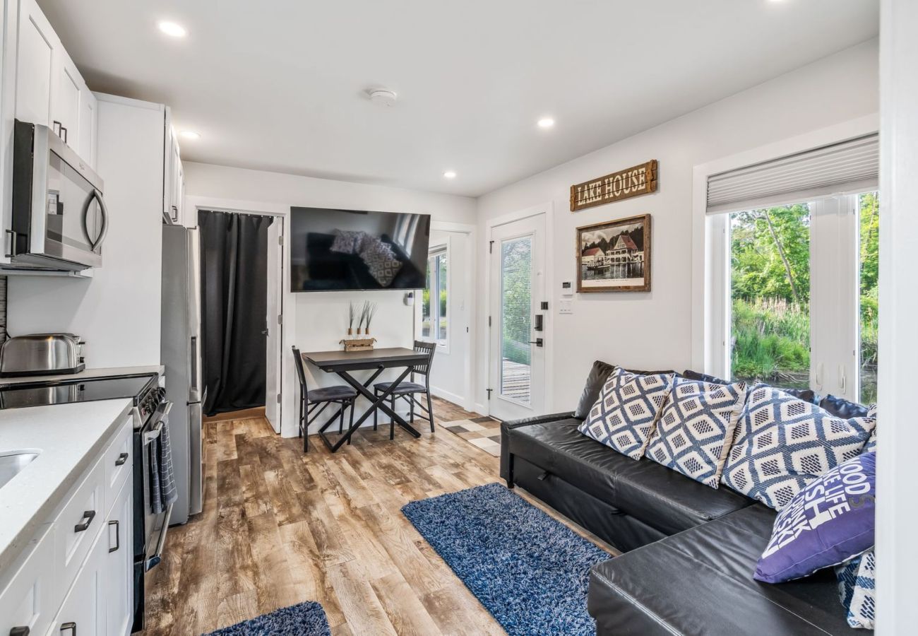 Living area with pull-out sectional sofa, dining table, modern kitchen, and large windows at Aqua Vista