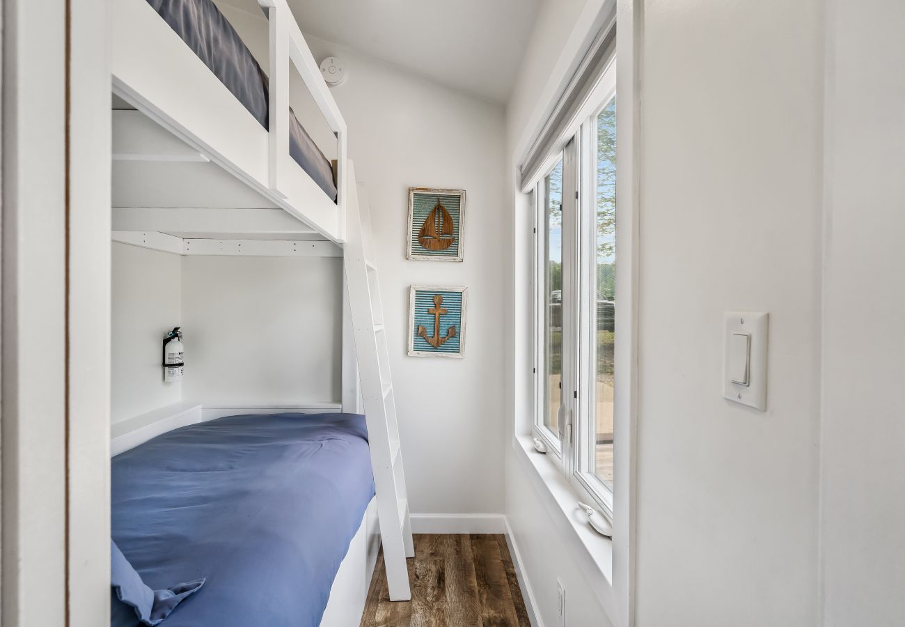 Built-in twin bunk bed with nautical wall art and window lighting at Aqua Vista Floating Cottage in South Haven, Michigan