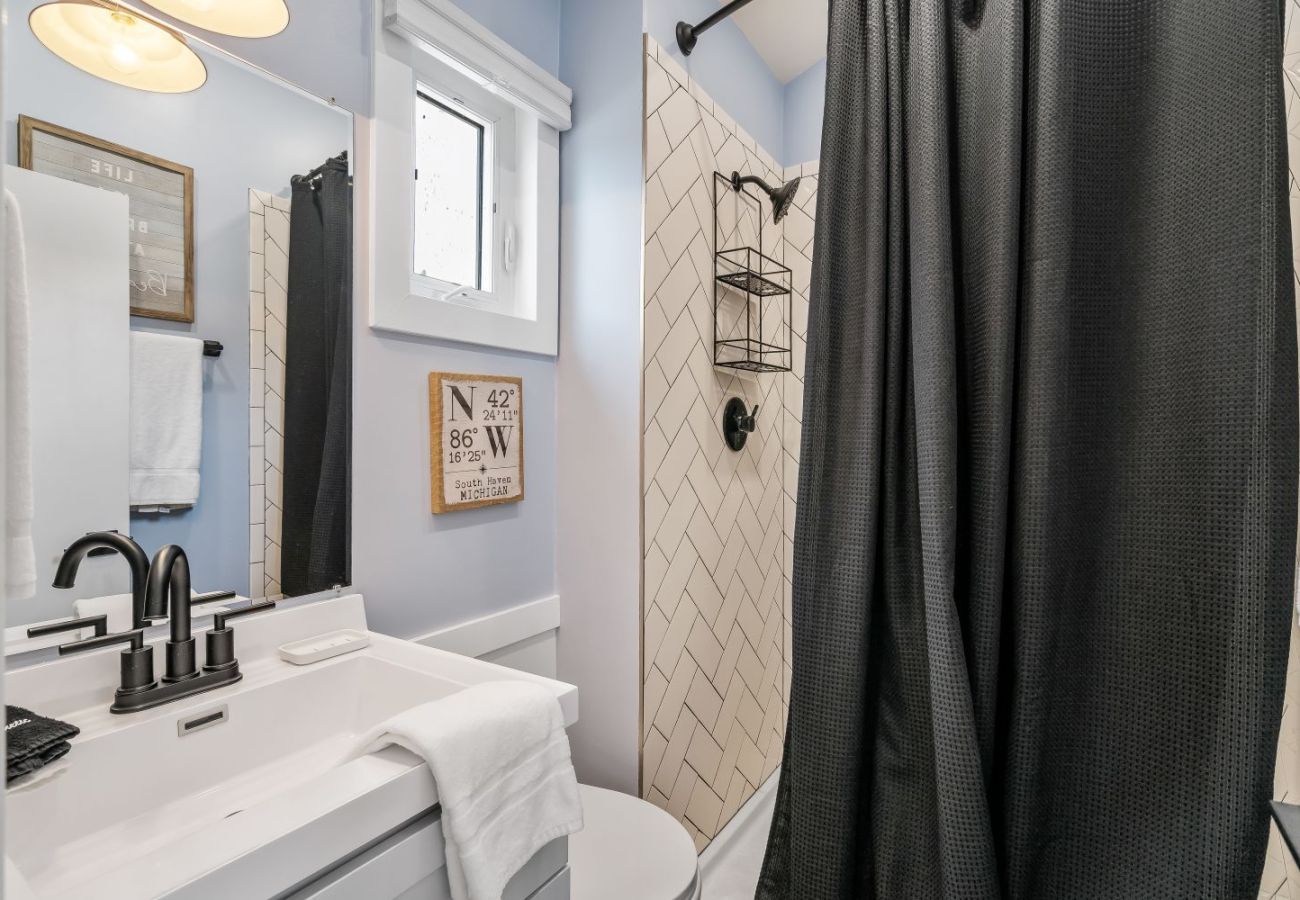 Bathroom with tiled shower, black fixtures, vanity sink at Aqua Vista