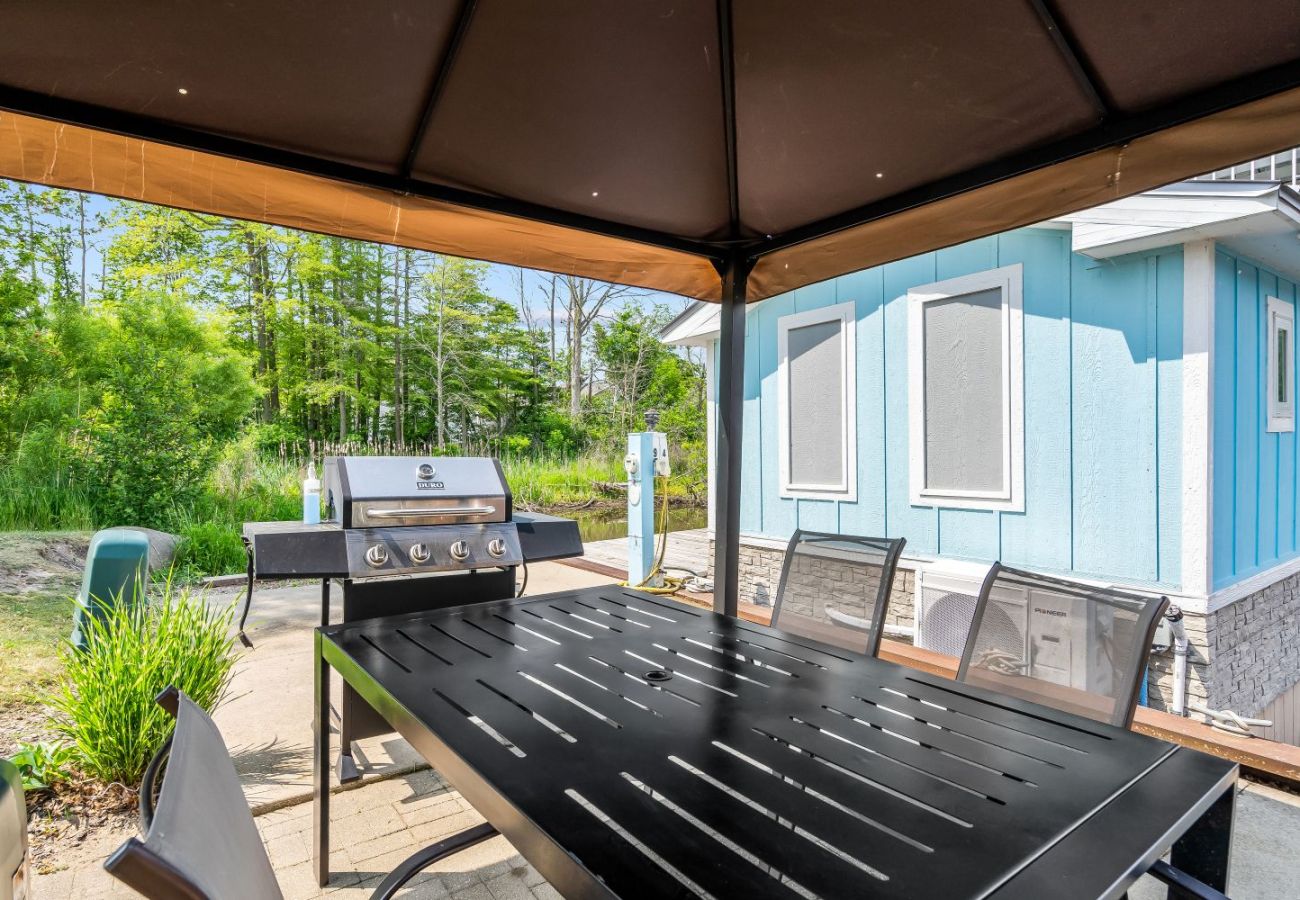 Shaded patio with dining table and gas grill
