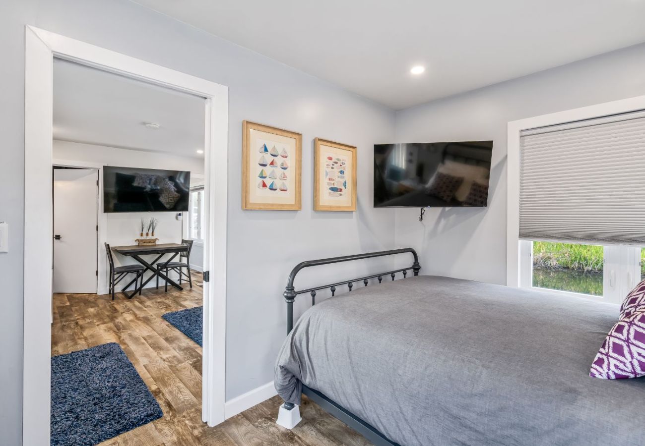 Primary bedroom with metal-frame bed and mounted TV at Aqua Vista Floating Cottage in South Haven, Michigan