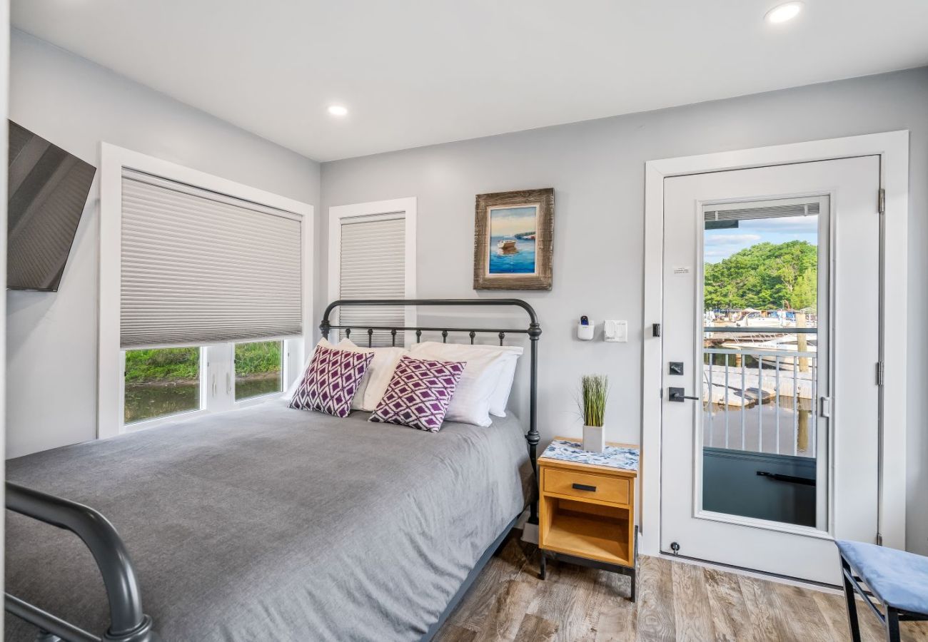 Bedroom with meal-frame bed, nightstand, and door opening to a waterfront deck at Aqua Vista in South Haven, Michigan