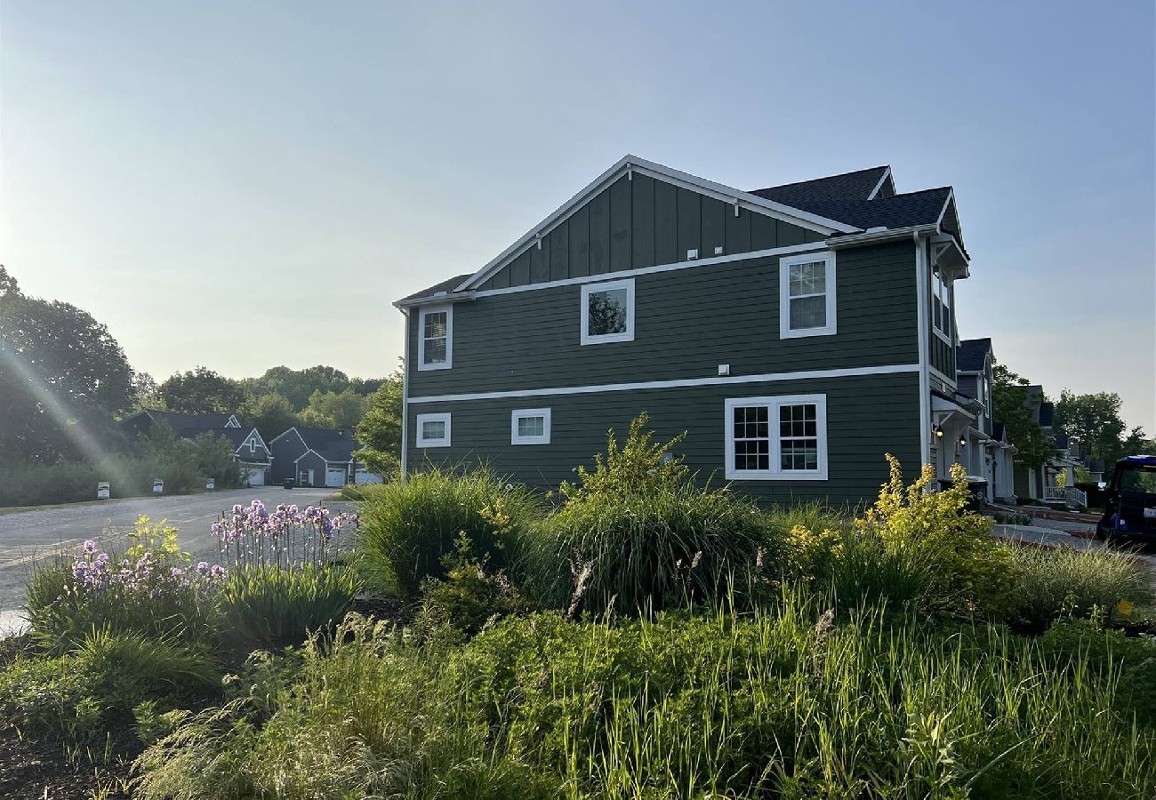 Side exterior view of Harbor Pointe home with green siding, white trim, and landscaped greenery.