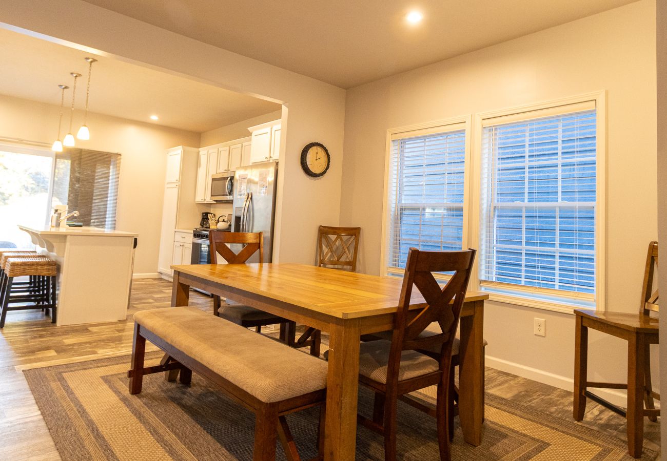 Harbor Pointe dining area with large wooden table, chairs, and bench seating, and open layout leading into the kitchen