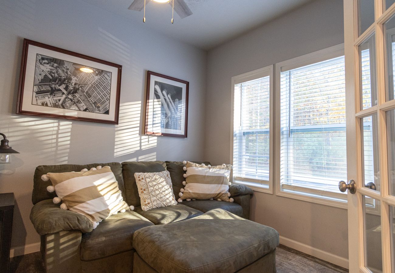 Harbor Pointe lounge room with pull-out sectional sofa, large windows, french doors, and framed wall art.