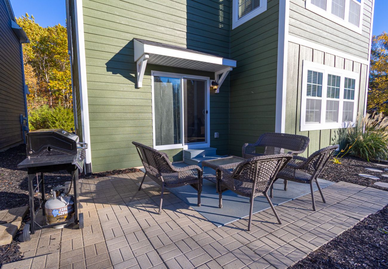 Harbor Pointe outdoor patio with wicker seating, small table, gas grill, and sliding door access