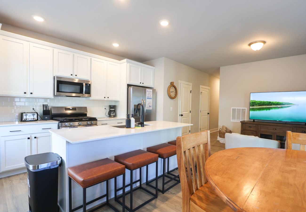 Bright open-concept kitchen with white cabinetry, stainless-steel appliances, and large island seating for four