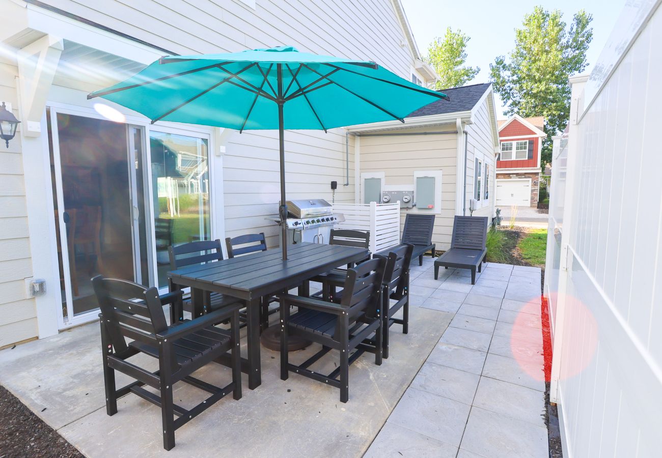 Private patio with large umbrella, stainless-steel grill and two lounge chairs at Blissful Daze
