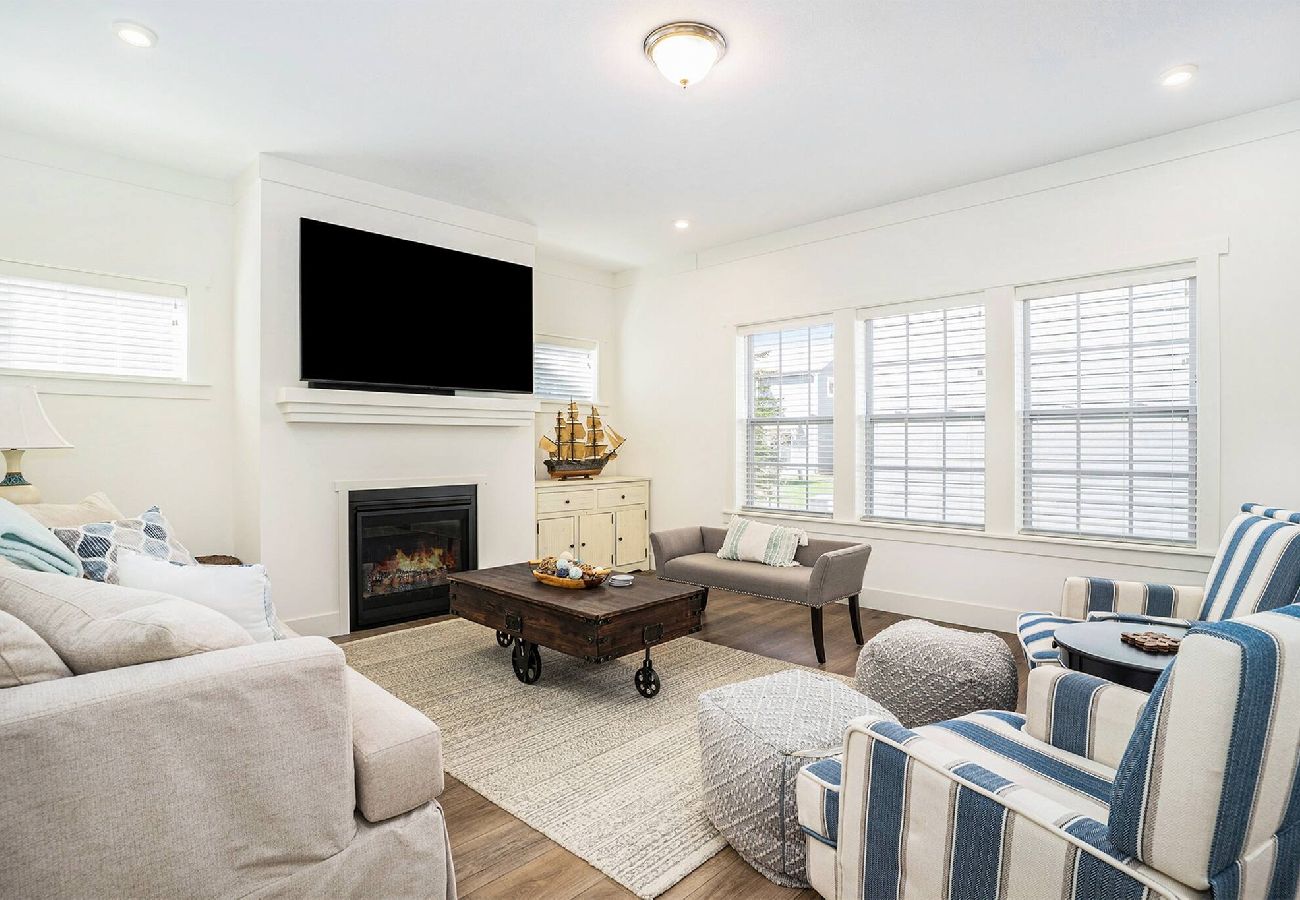 Bright living room with a fireplace, large wall-mounted TV, and coastal decor