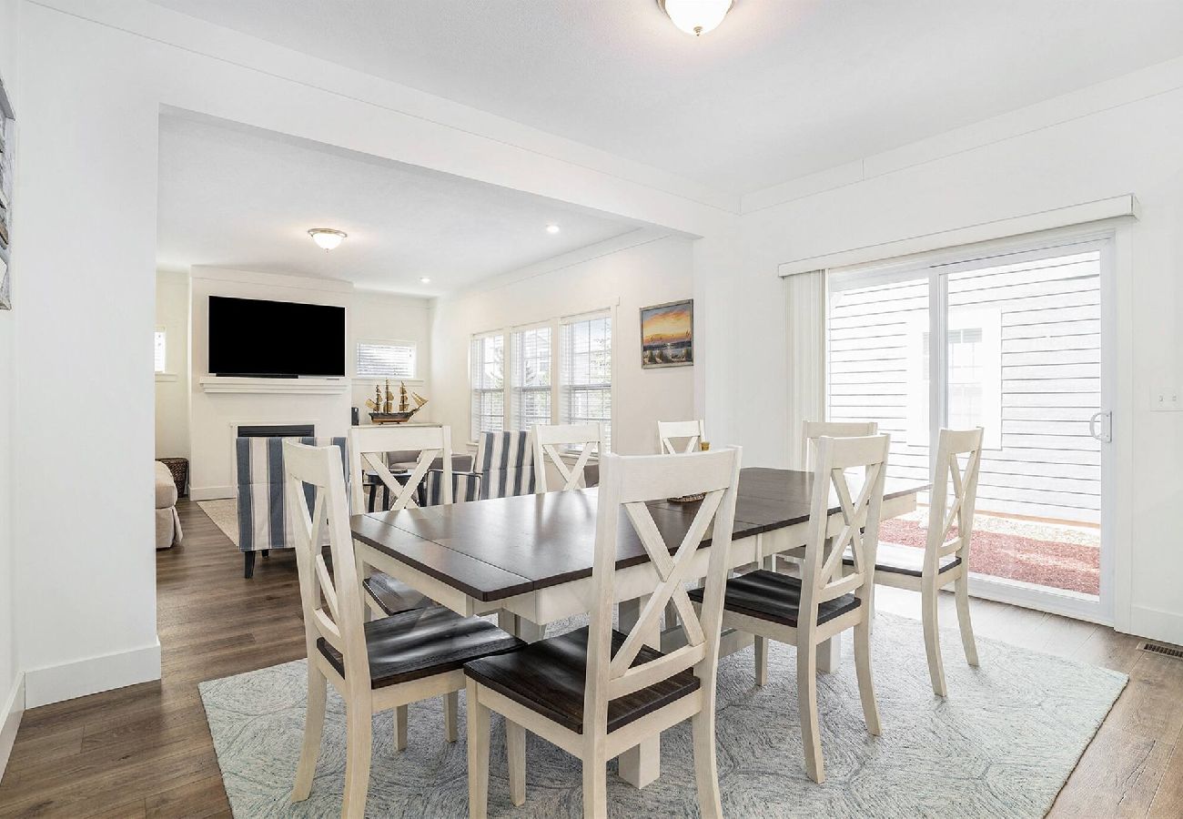 Dining room with a large table and eight chairs, sliding glass door to the patio, and a view into the adjoining living room
