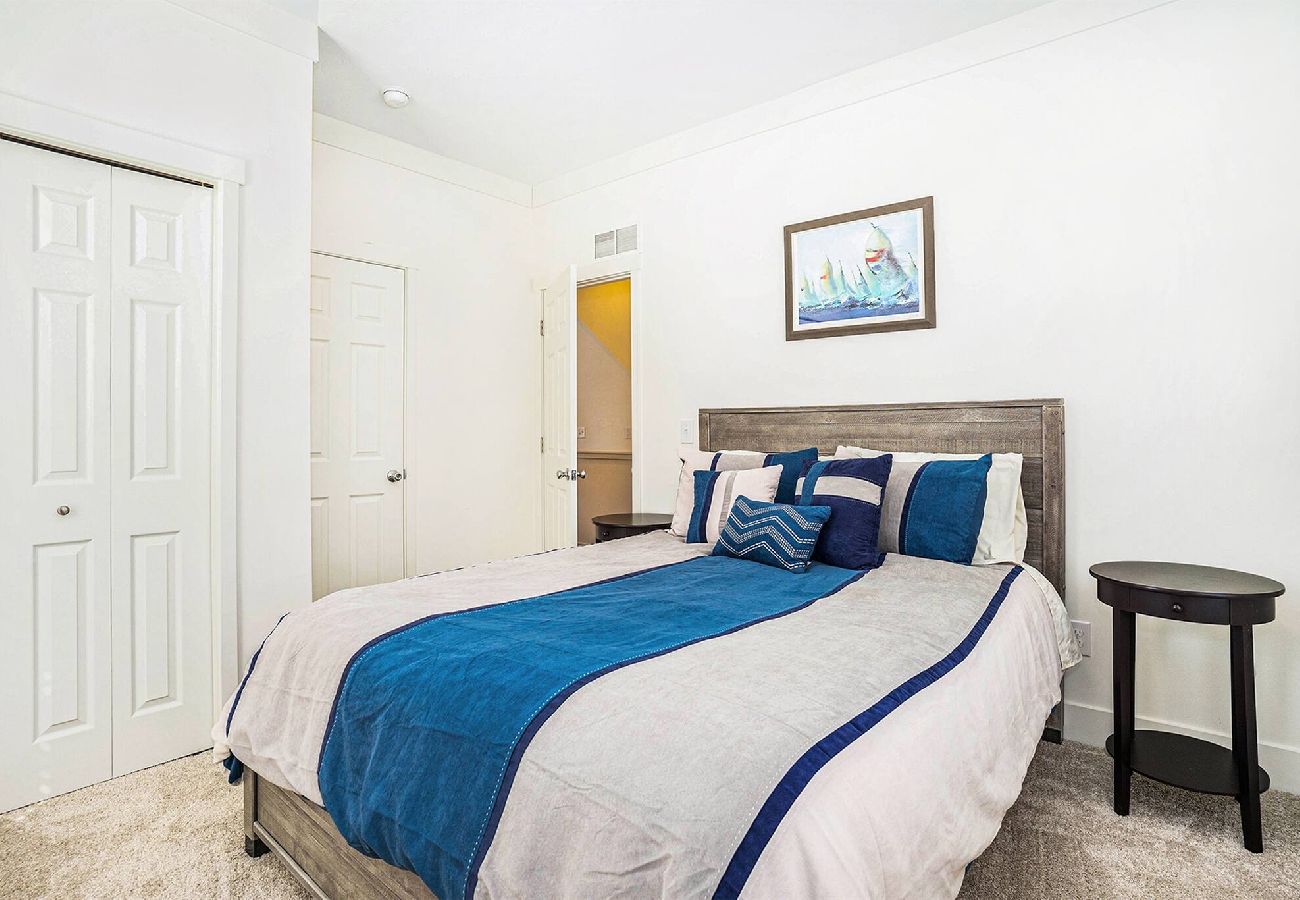 Bedroom with queen bed, a wooden headboard, side table, and double-door closet